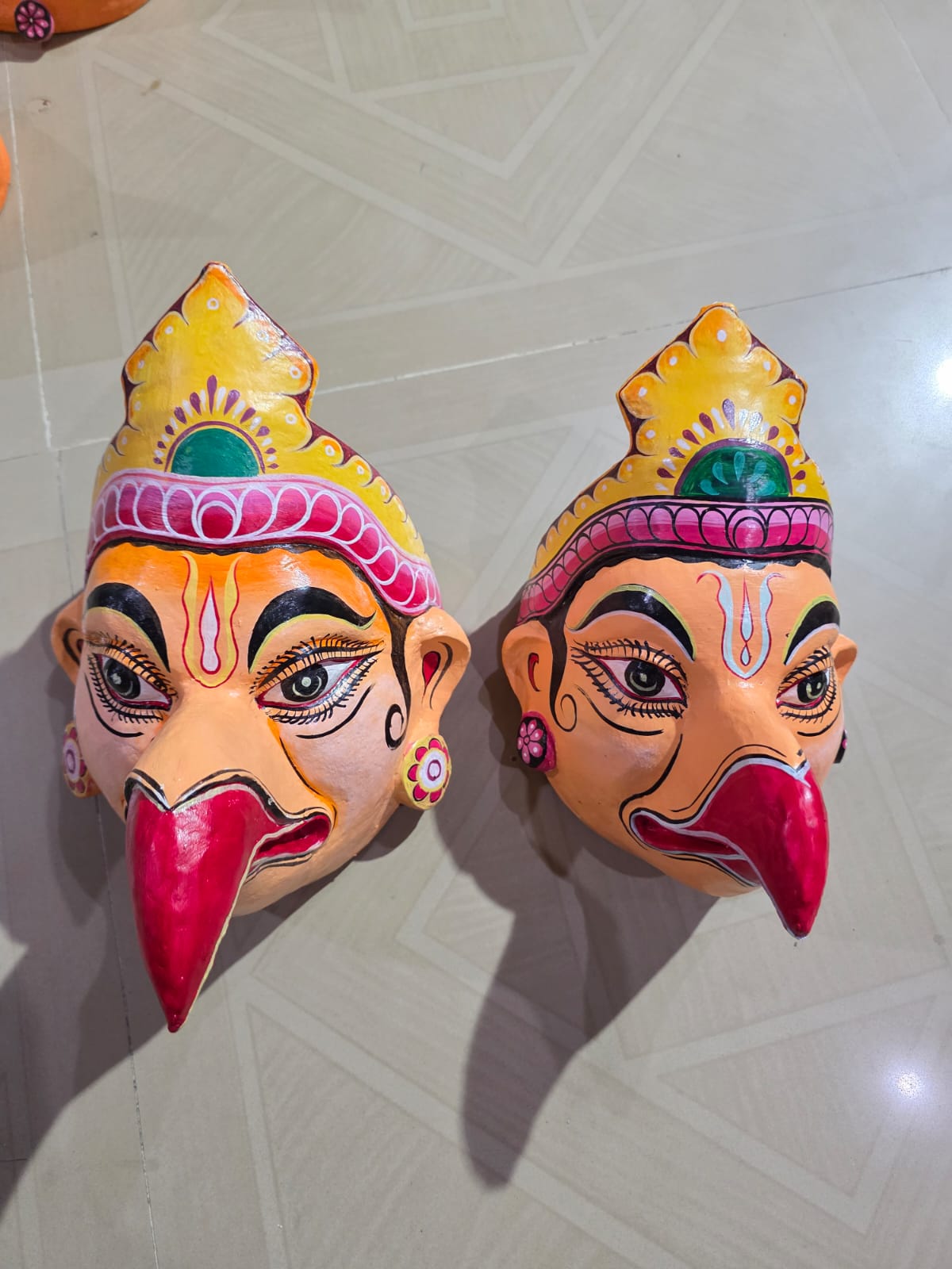 Two eagle-faced Jatayu masks with red beaks and painted crowns