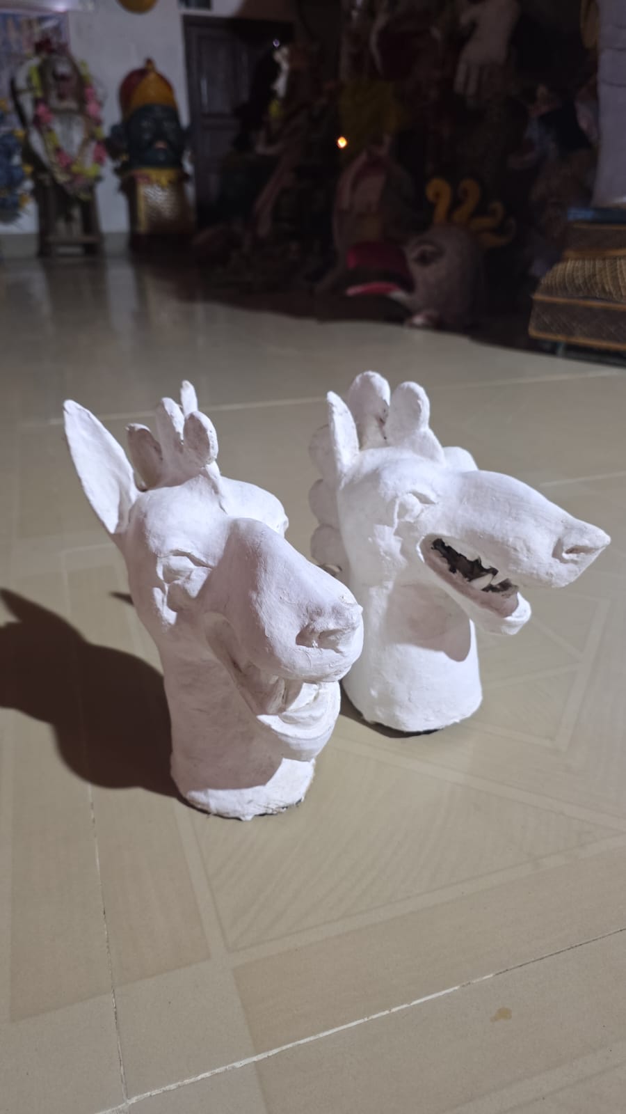 Two unfinished white horse-head masks drying in a workshop